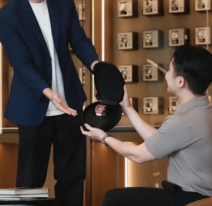 A seller handing over a watch to a Luxehouze specialist at the boutique
